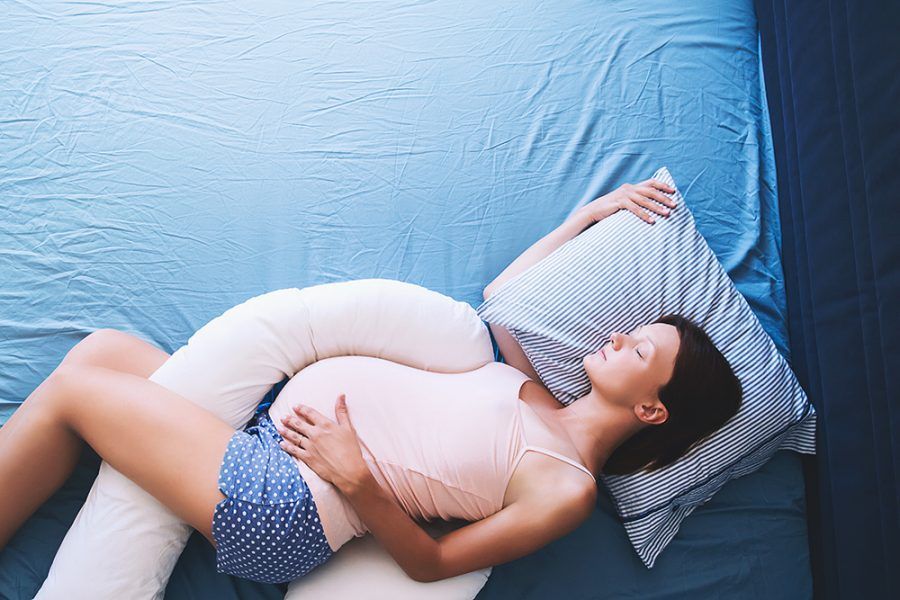 Photo of pregnant woman asleep on bed