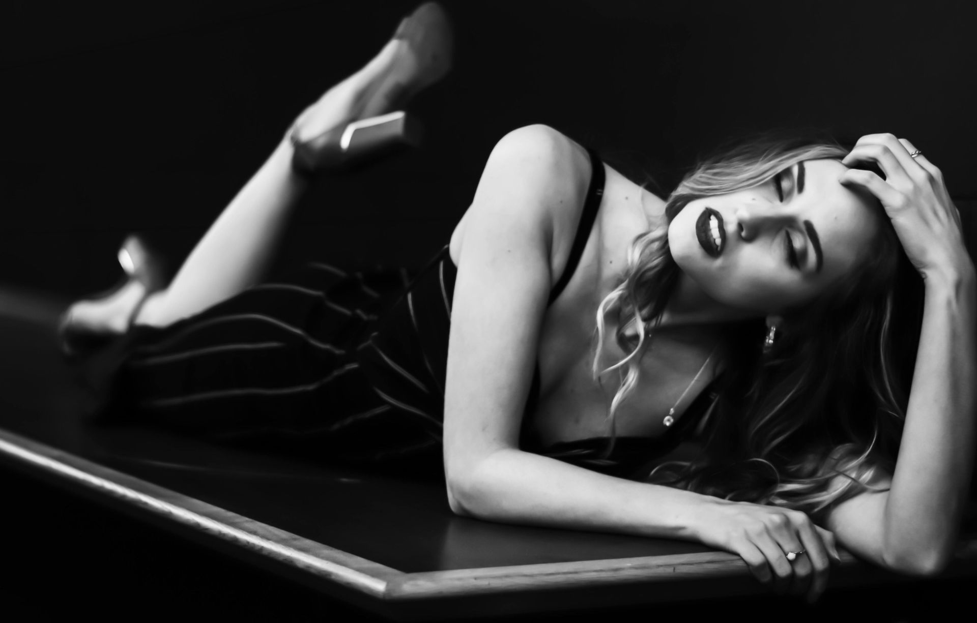 Elegant black and white portrait of a woman posing indoors in a glamorous setting.
