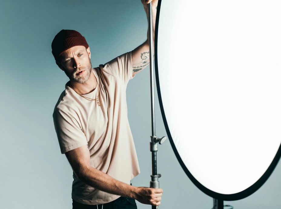 A professional photographer adjusting studio lighting while posing indoors.